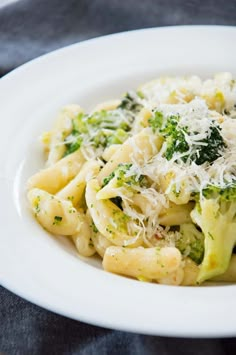 pasta with broccoli and parmesan cheese in a white bowl on a table