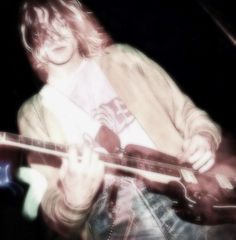 a man playing a guitar while standing in front of a microphone