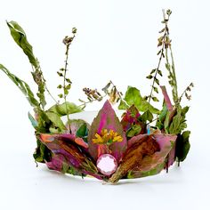 a vase filled with lots of flowers and green leaves on top of a white table