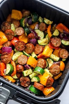 an air fryer filled with sausage and veggies