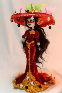 a doll dressed in red and yellow with a large hat on top of her head