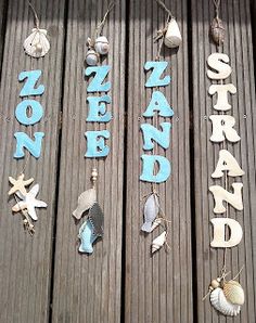 several wooden signs are hanging on the side of a wood fence with sea shells and seashells