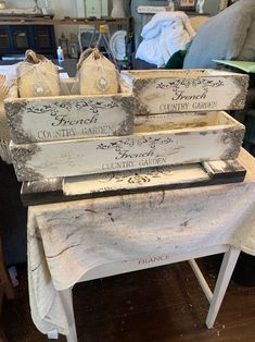 three wooden crates sitting on top of a table next to a white cloth covered chair