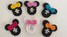 several crocheted mickey mouse ears are arranged on a white surface, including one with a pink bow