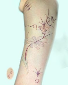 a woman's arm with flowers and butterflies tattoo on her left arm, while the other hand is holding an object