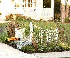 a white picket fence surrounded by flowers and grass