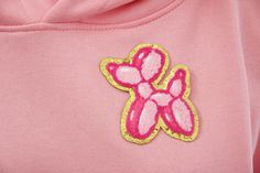 a close up of a pink hoodie with a yellow and pink flower on it