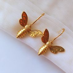 𝑯𝒂𝒏𝒅𝒎𝒂𝒅𝒆 𝒂𝒏𝒅 𝑴𝒊𝒏𝒊𝒎𝒂𝒍: Enhance your look with our dainty Bee Earrings for Women, perfect for those who are searching unique, funky and trending jewelry for their loved ones. These earrings feature Bumble Bee charms dangle drop earrings, 14k Gold Plated and secure fishhook are designed to be a minimal dainty gift for various occasions, including birthdays, parties, and as Christmas gifts. DETAILS: * Bee Dangle Earrings * 14k Gold Plated * Sold as a Pair * Comfortable & Lightweigh Danglers Earrings, Bug Jewelry, Bumble Bee Earrings, Trending Jewelry, Dangler Earrings, Gold Earrings For Women, Gold Bee, Jewelry Care Instructions, Bee Earrings