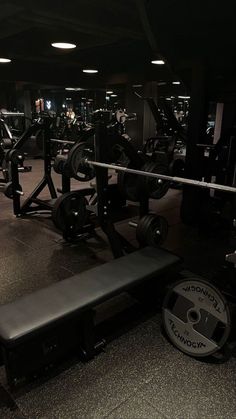 an empty gym with weight benches and barbells