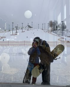 two snowboarders standing in front of a glass window