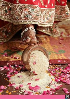 a person pouring rice into a bowl on top of a floor covered in flowers and petals