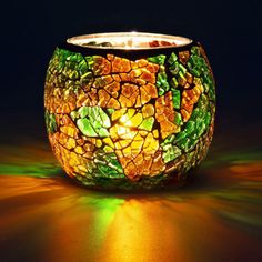 a lit candle is sitting on the floor with green and yellow lights in front of it