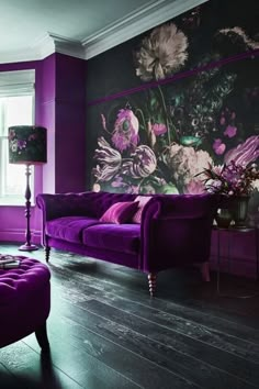 a living room with purple furniture and flowers painted on the wall behind it's couches