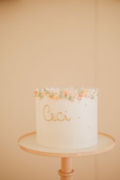 a white cake sitting on top of a wooden stand