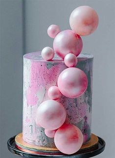 a pink and white cake with balloons on top