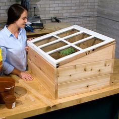 a woman standing next to a wooden box with plants in it