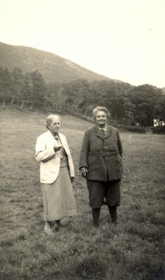 an old black and white photo of two people standing in a field