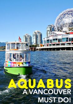 a green and white boat traveling on the water in front of a city with buildings