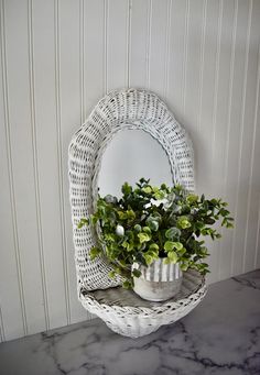 a white wicker basket holding a potted plant on top of a marble counter