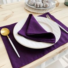 a white plate topped with purple napkins next to a bowl of donuts on top of a wooden table