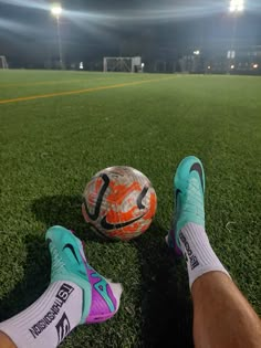 a soccer ball sitting on top of a field next to a person's feet