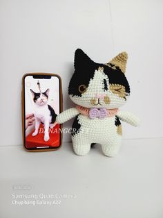 a small crocheted cat is next to a cell phone case with an image of a cat on it