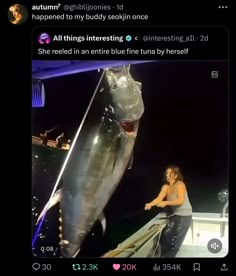 a woman standing next to a shark on top of a boat