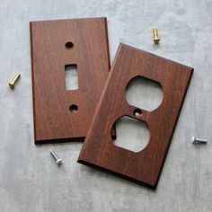 two wooden switch plates sitting on top of a table with screws next to them