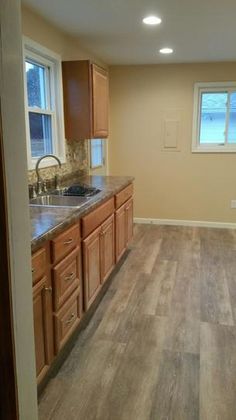 an empty kitchen with wooden cabinets and granite counter tops, along with hardwood flooring