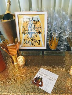 a table topped with lots of glasses next to a sign and some wineglasses