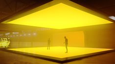 two people are standing in front of a yellow light that is shining on the floor