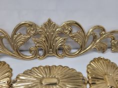 three pieces of gold colored metal on a white tablecloth with an ornate design and decorative details