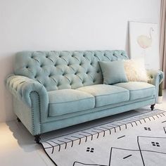 a living room with a blue couch and white rug on the floor next to a window