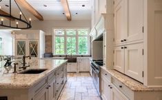 a large kitchen with white cabinets and marble counter tops, along with an island in the middle