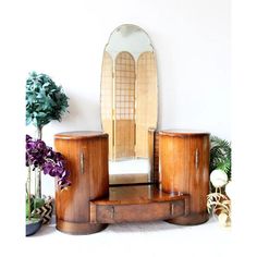 a mirror sitting on top of a wooden table next to two vases and a potted plant