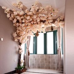 a room with flowers hanging from the ceiling and tiled flooring in front of a large window