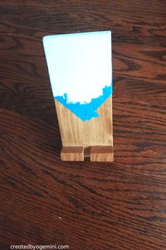 a piece of wood that has been painted with blue and white paint sitting on top of a wooden table