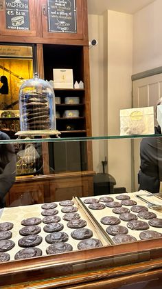 two people behind a glass counter with pastries in front of them on display at a bakery