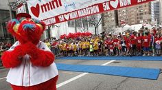 a large red mascot standing in front of a group of people on a city street