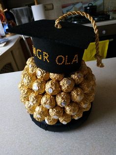 a graduation cap made out of gold chocolates on top of a black hat that says mr ola