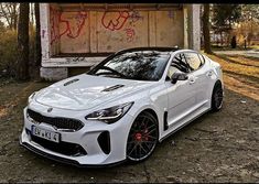 a white sports car parked in front of a building with graffiti on the wall behind it