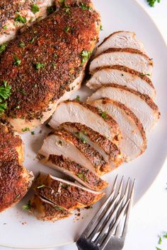 sliced chicken on a white plate with parsley sprinkled around the top and sides