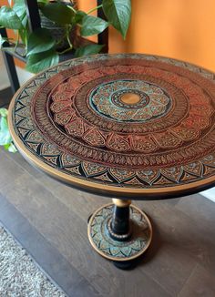 an ornately decorated cake plate sitting on top of a wooden table next to a potted plant