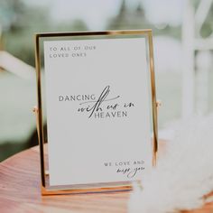 a sign that says dancing we are in heaven on top of a wooden table with feathers