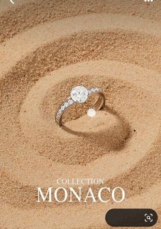 a diamond ring sitting on top of sand with the words collection monaco written below it