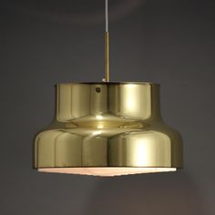 a gold colored light fixture hanging from the ceiling in a room with grey walls and flooring