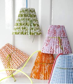 four different colored paper lamps hanging on the wall