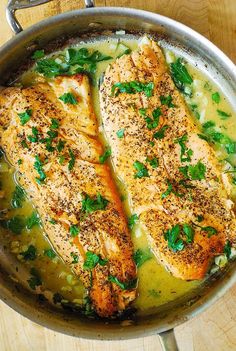 two fish fillets in a skillet on a wooden table