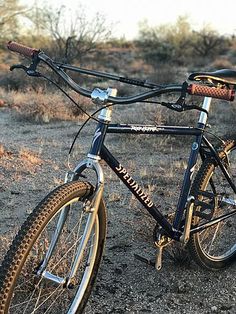 a bicycle parked in the middle of a dirt field with no grass on it,