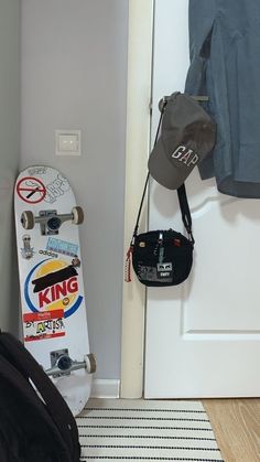 a skateboard is propped up against the wall next to a door with a hat hanging on it